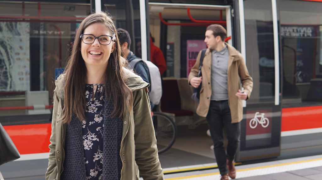 Woman smiles walking off tram